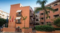 Einladende Außenansicht des Artemis Hotels mit mediterranem Flair, Palmen und kleinen Balkonen – zentral gelegen für einen entspannten Urlaub in Italien.