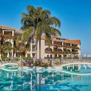 Weitläufige Poolanlage mit eleganter Brücke, umgeben von tropischer Bepflanzung und blühenden Bougainvillea – ideal für entspannte Stunden unter südlicher Sonne.