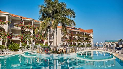 Weitläufige Poolanlage mit eleganter Brücke, umgeben von tropischer Bepflanzung und blühenden Bougainvillea – ideal für entspannte Stunden unter südlicher Sonne.