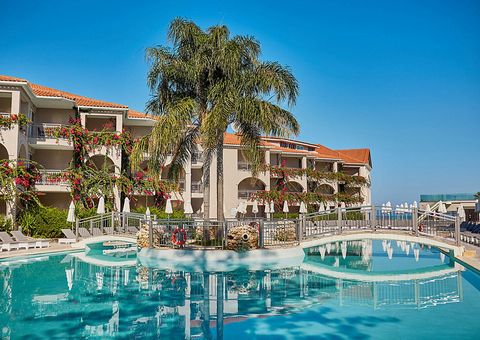 Weitläufige Poolanlage mit eleganter Brücke, umgeben von tropischer Bepflanzung und blühenden Bougainvillea – ideal für entspannte Stunden unter südlicher Sonne.