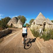 Radfahrerin bei Trulli-Häusern in Apulien ©Richard NashWirestock Creators, AdobeStock Radfahrerin bei Trulli-Häusern in Apulien